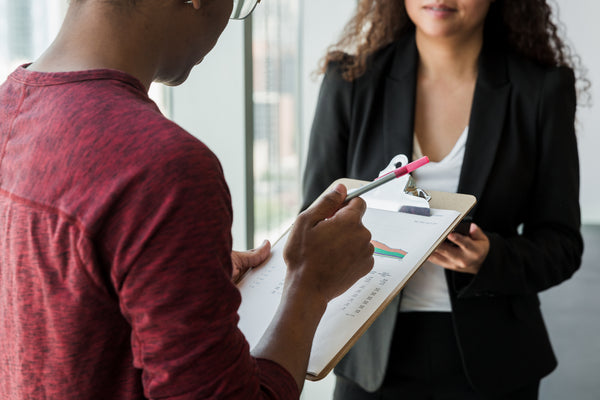Close-up of a team member pointing to charts on a clipboard while reviewing project metrics.