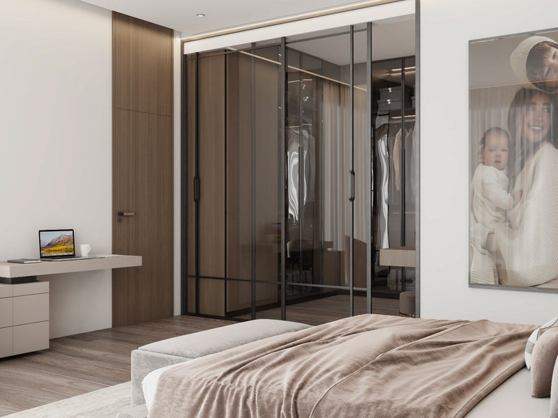 Modern master bedroom with glass wardrobe, desk, and bed with brown blanket.