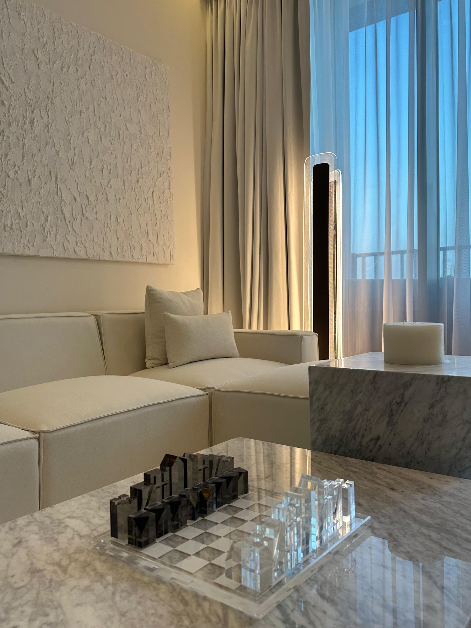 Luxury apartment interior with sheer curtains, a unique spiral chandelier, and a neutral, plush aesthetica