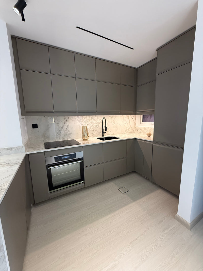 Modern kitchen interior with gray cabinets and marble countertop.