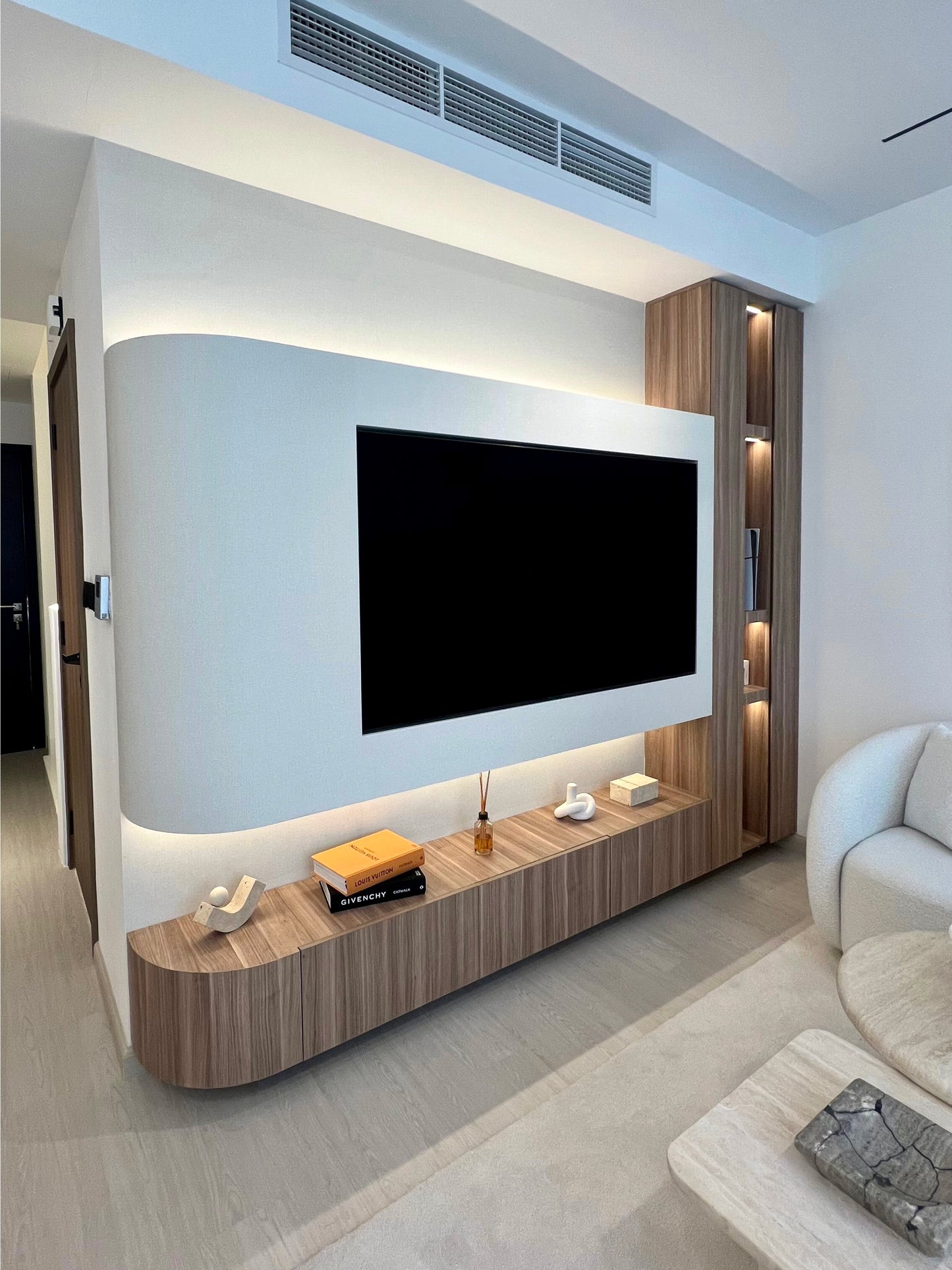 Modern living room with a large TV mounted on the wall and a wooden entertainment console.