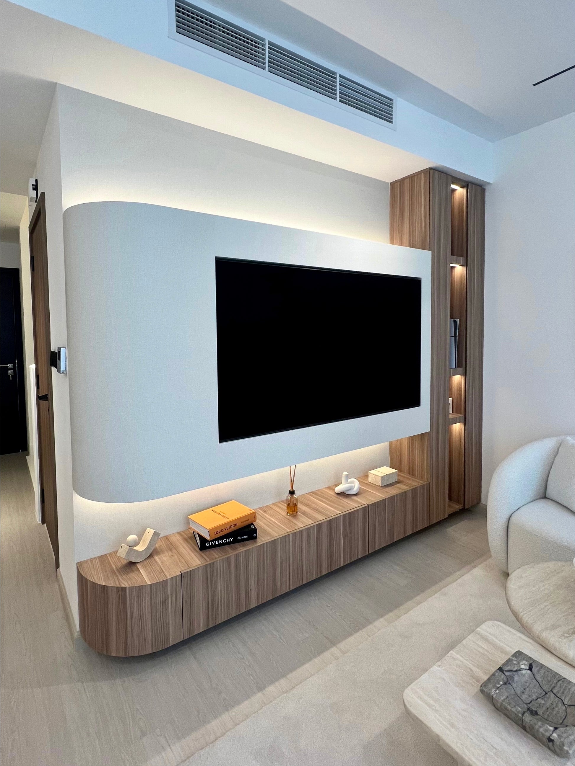 Modern living room with a large TV mounted on the wall and a wooden entertainment console.