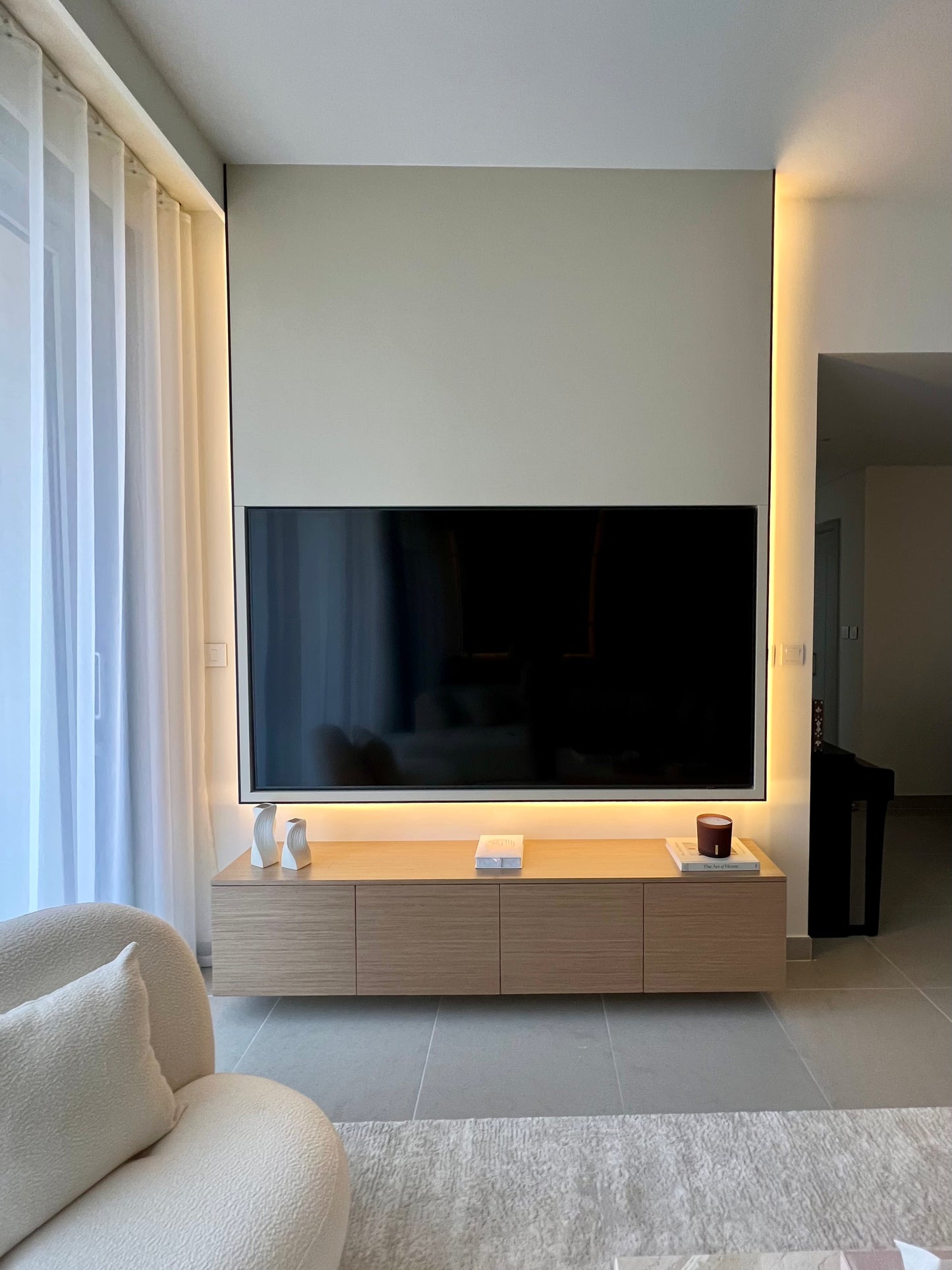Modern living room with a large flat-screen TV mounted on a wall above a wooden cabinet.