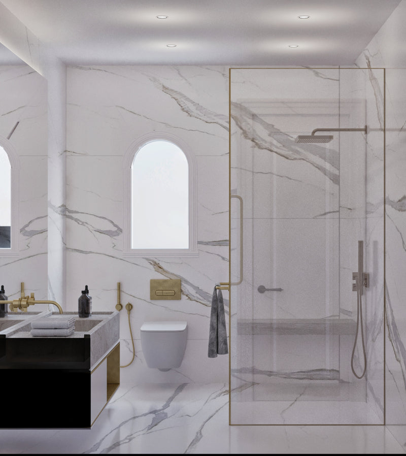 Modern master bedroom's bathroom with marble walls, glass shower enclosure, and gold fixtures.