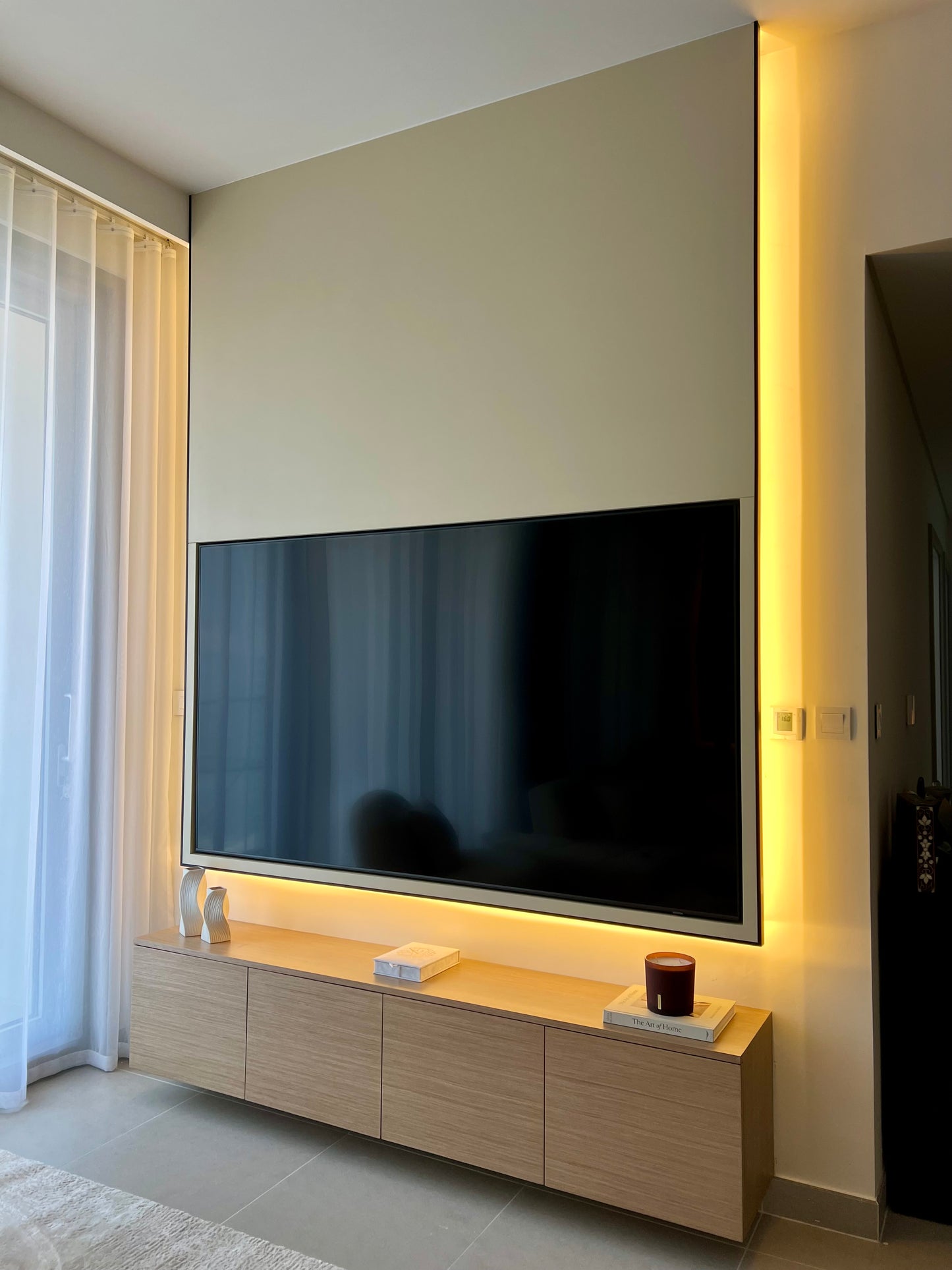 Modern living room with a large flat-screen TV mounted on a wall with built-in lighting.